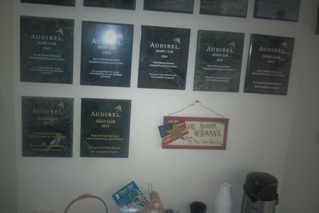 Audibel plaques on wall above table with coffee