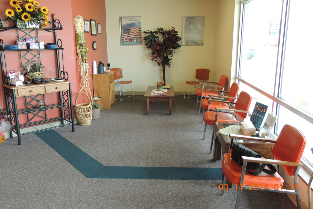 Waiting room with orange chairs lining right wall in front of windows